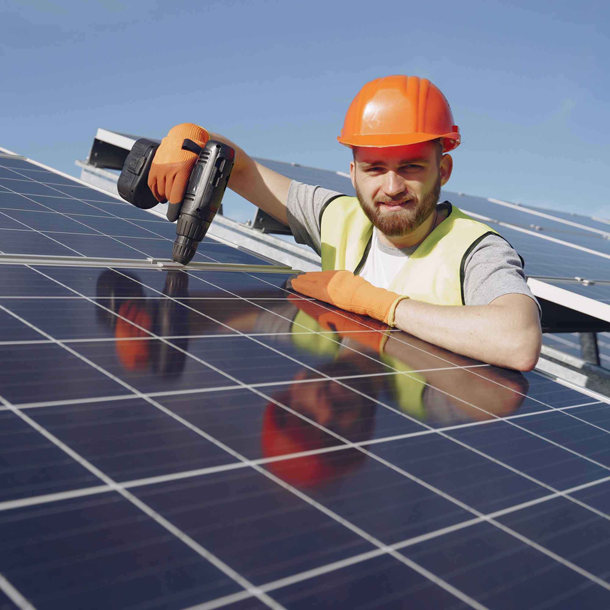 Installer installing a solar panel using a drill with orange cap